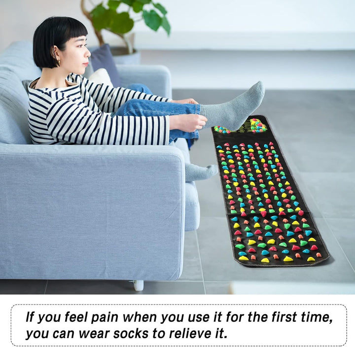 Person sitting on a couch with a colorful mat on the floor next to them.