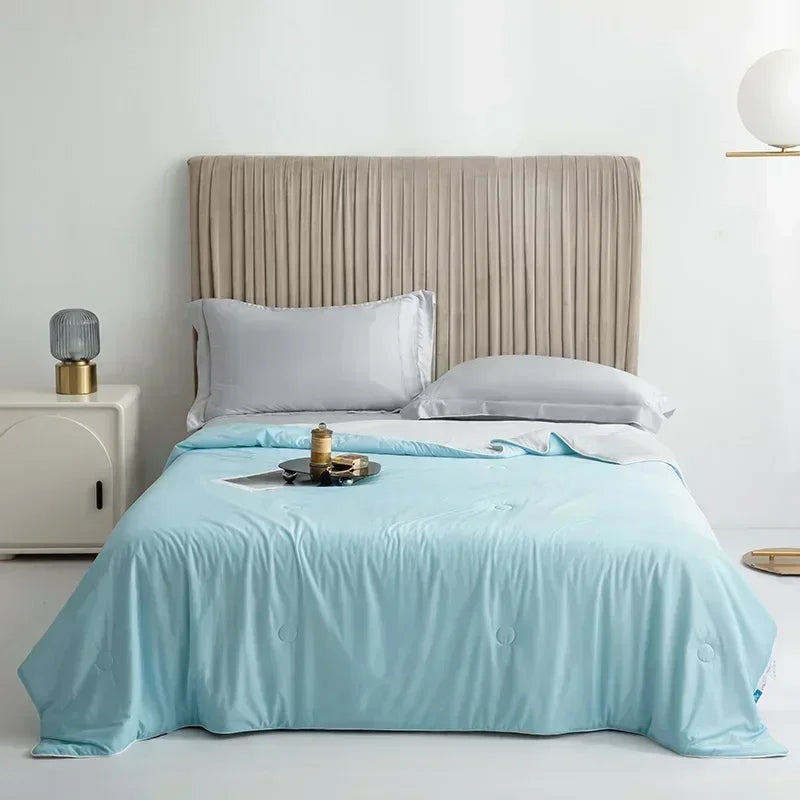 Bed with light blue comforter and beige headboard in a room setting.