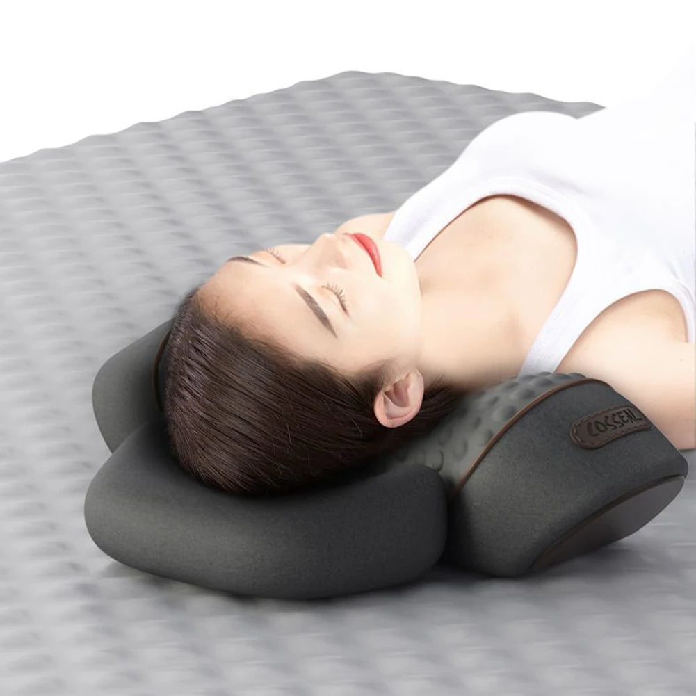Person lying on a gray surface with a neck pillow, wearing a white tank top.