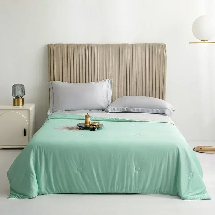 Bed with mint green comforter and beige headboard in a bedroom setting.